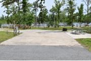 ADA-accessible campsite with concrete pad, picnic table, cooking grill with electric and water in a campsite with view of lake.