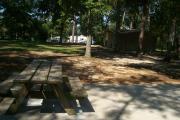 Picnic table on concrete pad with view of building.