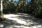 This campsite is tucked back in the shady hammock which provides cover most of the day. There is vegetation providing a boundary from neighboring sites. The ground cover is crushed shell, making a hard packed white surface.