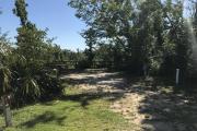 Full view of Campsite 1 from road. Electrical hookup is located on right side and water hookup is located on left side of site. Picnic table and fire ring are located near the back of site to the left.