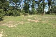 View of picnic table, fire ring, and clothes line located near back of site. Electrical hookup is located on the right side and water hookup is located on the left side of the site