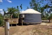 View of the inside of the YURT showing one queen bed, a chair, and a dresser.