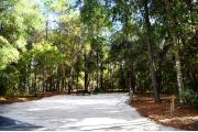 Campsite #7 at Wekiwa Springs State Park has a crushed shell surface and is surrounded by sections of split rail fence and trees creating partial shade on the site.  A picnic table and in-ground fire ring/grill are provided on the site along with water and 30amp electrical service.