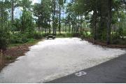 Campsite #8 at Wekiwa Springs State Park has a crushed shell surface and is surrounded by sections of split rail fence and trees creating partial shade on the site.  A picnic table and in-ground fire ring/grill are provided on the site along with water and 30amp electrical service.