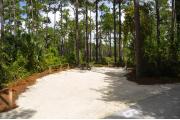 Campsite #9 at Wekiwa Springs State Park has a crushed shell surface and is surrounded by sections of split rail fence and tall Pines creating partial shade on the site.  A picnic table and in-ground fire ring/grill are provided on the site along with water and 30amp electrical service.