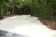 Campsite #10 at Wekiwa Springs State Park has a crushed shell surface and is surrounded by sections of split rail fence and trees creating partial shade on the site.  A picnic table and in-ground fire ring/grill are provided on the site along with water and 30amp electrical service.