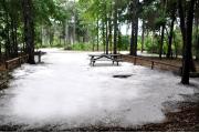 This photo is from the back of the site and shows the campground road.  The fire ring/grill is located towards the back of the site and the site is surrounded by sections of low, split rail fence.