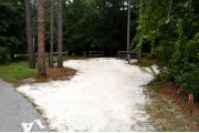Campsite #14 at Wekiwa Springs State Park has a crushed shell surface and is surrounded by sections of split rail fence and Pine trees creating partial shade on the site.  A picnic table and in-ground fire ring/grill are provided on the site along with water and 30amp electrical service.  A path from the back of the site leads to the bathhouse.