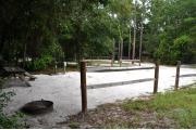 This photo is from the back corner of the site and shows the campground road and the bathhouse across the way.  The fire ring/grill is located in the back corner of the site and the site is surrounded by sections of split rail fence.