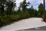 Campsite #17 at Wekiwa Springs State Park has a crushed shell surface and is surrounded by sections of split rail fence and trees creating partial shade on the site.  A picnic table and in-ground fire ring/grill are provided on the site along with water and 30amp electrical service.