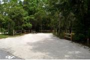 Campsite #18 at Wekiwa Springs State Park has a crushed shell surface and is surrounded by sections of split rail fence and trees creating partial shade on the site.  A picnic table and in-ground fire ring/grill are provided on the site along with water and 30amp electrical service.