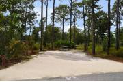 Campsite #19 at Wekiwa Springs State Park has a crushed shell surface and is surrounded by sections of split rail fence and trees creating partial shade on the site.  A picnic table and in-ground fire ring/grill are provided on the site along with water and 30amp electrical service.