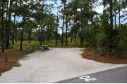 Campsite #20 at Wekiwa Springs State Park has a crushed shell surface and is surrounded by sections of split rail fence and trees creating partial shade on the site.  A picnic table and in-ground fire ring/grill are provided on the site along with water and 30amp electrical service.