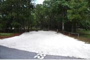 Campsite #22 at Wekiwa Springs State Park has a crushed shell surface and is surrounded by sections of split rail fence and trees creating partial shade on the site.  A picnic table and in-ground fire ring/grill are provided on the site along with water and 30amp electrical service.