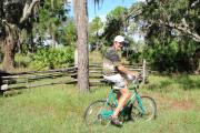 A Lake Kissimmee State Park visitor cruising on his teal colored bicycle through the pine trees.
