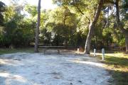 38x18 foot shell rock site with water and electric hook ups and a picnic table. 5 pine trees border this site and one pine tree stands in the middle of the site.