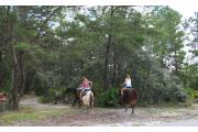 A view of three ladies on horse back entering the head of the multiuse trail.