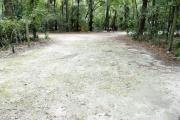 A September view of the campground drive from within campsite #8.  The water hookup is seen on the left.  Another campsite is visible across the campground drive.  Site is surrounded on three sides by a mixed oak, pine, and cabbage palm forest.