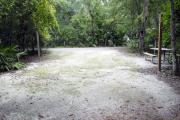 A September view of the campground drive from within campsite #11.  The water hookup is seen on the left, picnic table and lantern post are seen on the right.  Site is surrounded on three sides by a mixed oak, pine, and cabbage palm forest.