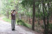 A hiker looks for birds while standing on the bridge over Big Creek.