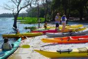 A family of 4 tries out colorful kayaks during a festival on Lake Louisa.