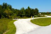 A 90 feet long gravel pull through campsite with vegetation giving privacy to the left side of the site. The sitting area is also located to the left and has a wooden picnic table and a cast-iron fire circle. Water and electric hook-ups are on the right hand side of the site.