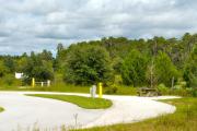 A 85 feet long gravel pull through campsite with vegetation giving some privacy to the right. The sitting area is also located to the right and has a wooden picnic table and a cast-iron fire circle. Water and electric hook-ups are on the left hand side of the site.