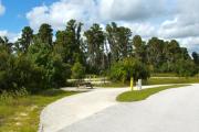 A 65 feet long gravel pull through campsite with vegetation giving some privacy to the left. The sitting area is also located to the left and has a wooden picnic table and a cast-iron fire circle. Water and electric hook-ups are on the right hand side of the site.