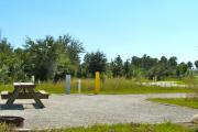 A gravel sitting area with a wooden picnic table and a cast-iron fire circle.