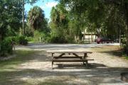 Looking toward campground road from site; picnic table and fire ring at rear of site; water and electrical hook up on left; site partially shaded in afternoon