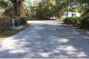 Looking out of site toward campground road; water spigot and electrical hook up on left; picnic table on the right; site is paved