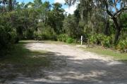 Looking into campsite from campground road; site mostly shaded in afternoon; water spigot and electrical hook up on right