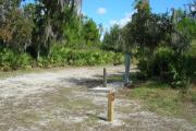Looking at campsite marker #9; site mostly sunny in afternoon; water spigot and electrical hook up on right