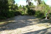 Looking into site from campground road; water spigot and electrical hook up on right; site mixture of grass and sand
