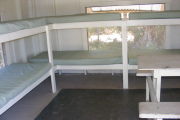 Six bunks with mattresses and a picnic table.