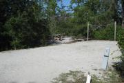 View of a picnic table, fire ring, and clothesline poles in partial shade.