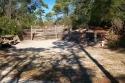 A view of the campsite with a shell/sand base and wooden retaining wall.