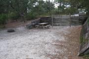 A view of the campsite with a shell/sand base and wooden retaining wall.