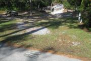 A view of the campsite with a shell/sand base and wooden retaining wall.