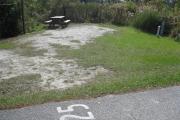 A view of the campsite with a shell/sand/grass base in bright sunshine.
