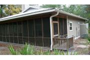 This picture of cabin 1 is taken from the corner to show one side of the cabin and the full length screened in porch. The porch is L shaped and runs the full length of both sides of the cabin. The porch has a wooden picnic table, chairs and a swing for your use. The porch has two access doors, one from the kitchen and the other is on the back side (other part of L shaped porch) between the fireplace and bedroom walls. The kitchen has a refrigerator, stove, range top, sink and dishwasher.