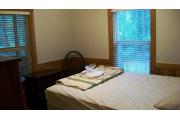 This photo shows the bedroom with the queen bed. There is a table and dresser with alarm clock in this room. The fireplace and living room are behind the picture taker.