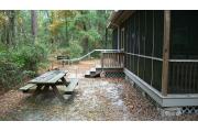 Oh, did I mention the wooden picnic table that is located out back with a fire ring and separate grill?  Well, each cabin has these added features. Each cabin also has two rocking chairs on the porch that is common to cabins 1-4. The porch is L shaped and runs the full length of both sides of the cabin. The porch has a wooden picnic table, chairs and a swing for your use. The porch has two access doors, one from the kitchen and the other is on the back side (other part of L shaped porch) between the fireplace and bedroom walls. The kitchen has a refrigerator, stove, range top, sink and dishwasher.
