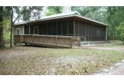 This views a ramp that enters the back screed in porch from the back side of the cabin. Notice the back porch does not run the full length of the cabin. However, in addition to the two doors that cabins 1-4 have that enter the back porch, cabin 5 has a third door which enters the porch from the bedroom.