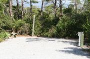 Picnic table on the left of a narrow back-in site. Electric and water hookups are on the right.