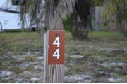 Close-up photo of the brown with white site number sign on a wooden post.