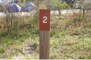 Close-up photo of the brown with white site number sign on a wooden post.