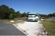 This photo shows a RV on the gravel pad. There is only grass surrounding this site.