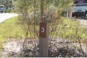 Close-up photo of the brown with white site number sign on a wooden post.