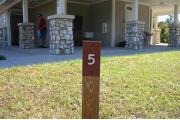 Close-up photo of the brown with white site number sign on a wooden post.